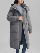 Ein-langer-Steppmantel-mit-Kapuze-und-großen-Taschen,-ideal-für-den-winterlichen-Stil-und-warme-Tage.