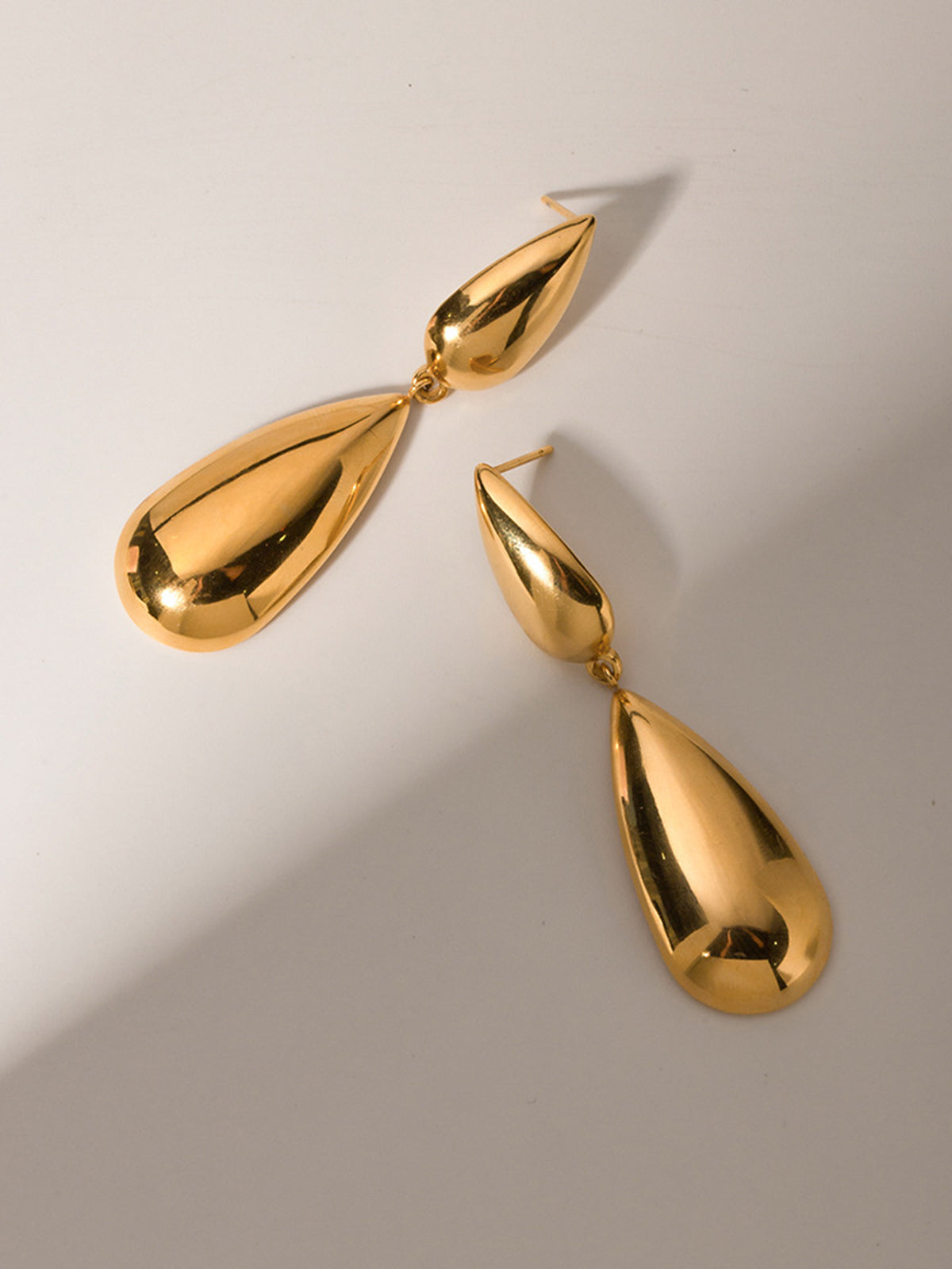 Ein-Paar-goldene-tropfenförmige-Ohrringe-an-einem-Ohr