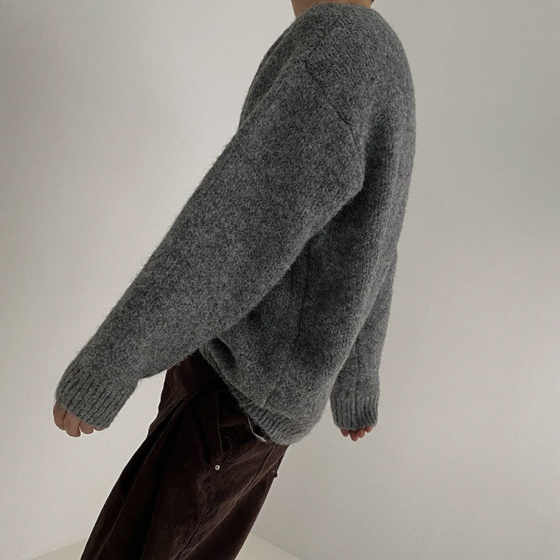 Seitenansicht eines grauen Pullovers, getragen von einem Modell mit lässigem Look.