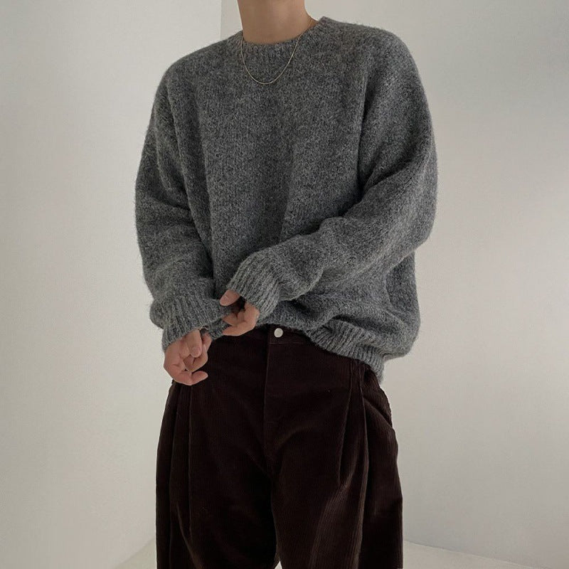 Detailaufnahme eines Modells im grauen Pullover mit leicht aufgekrempelten Ärmeln, betont die weiche Textur des Stoffes.
