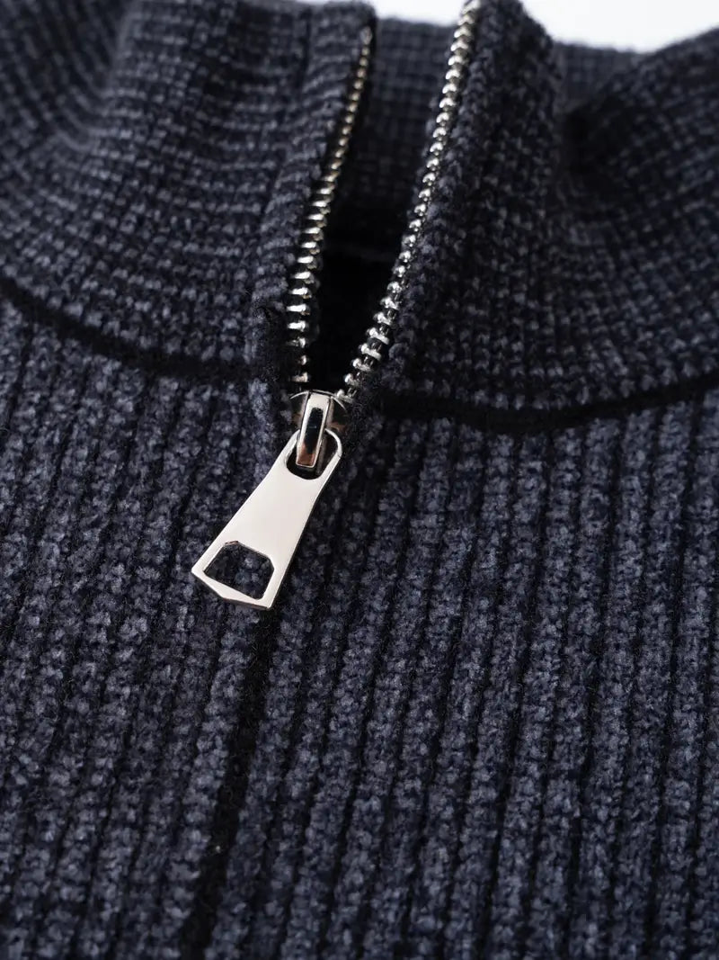 Ein-dunkelblauer-Pullover-mit-Reißverschluss-und-weißem-schneeflockenartigem-Muster.