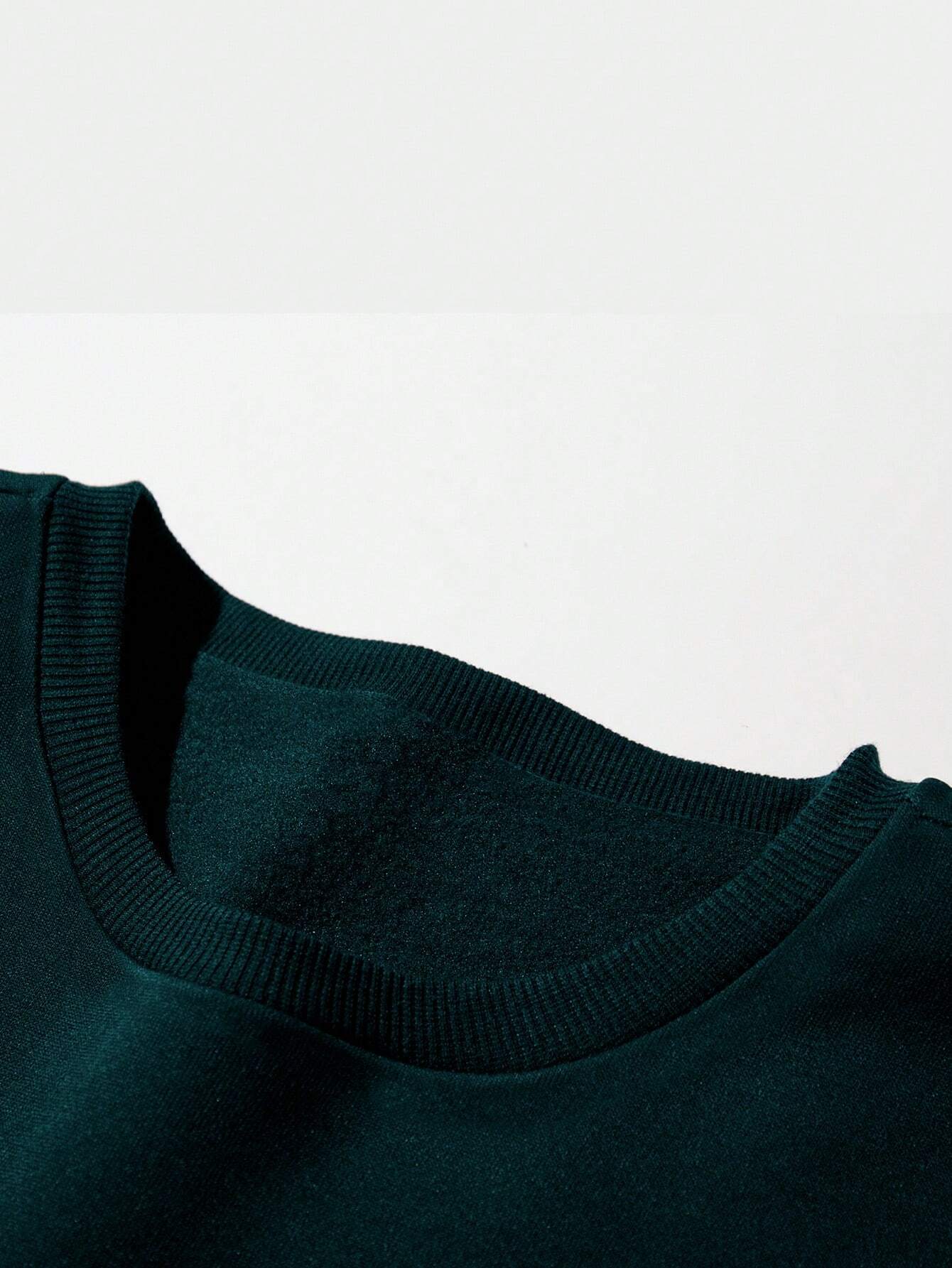 Ein-dunkelgrüner-Pullover-mit-drei-Weihnachtsmännern-und-dem-Schriftzug