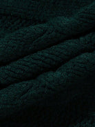 Ein-Mann-trägt-einen-dunkelgrünen-Strickpullover-mit-Zopfmuster,-perfekt-für-einen-warmen-und-stilvollen-Winterlook