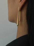 Ein-Paar-schlank-silber-gold-tropfenförmige-Ohrringe-an-einem-Ohr.