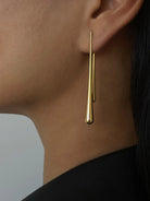 Ein-Paar-schlank-silber-gold-tropfenförmige-Ohrringe-an-einem-Ohr.