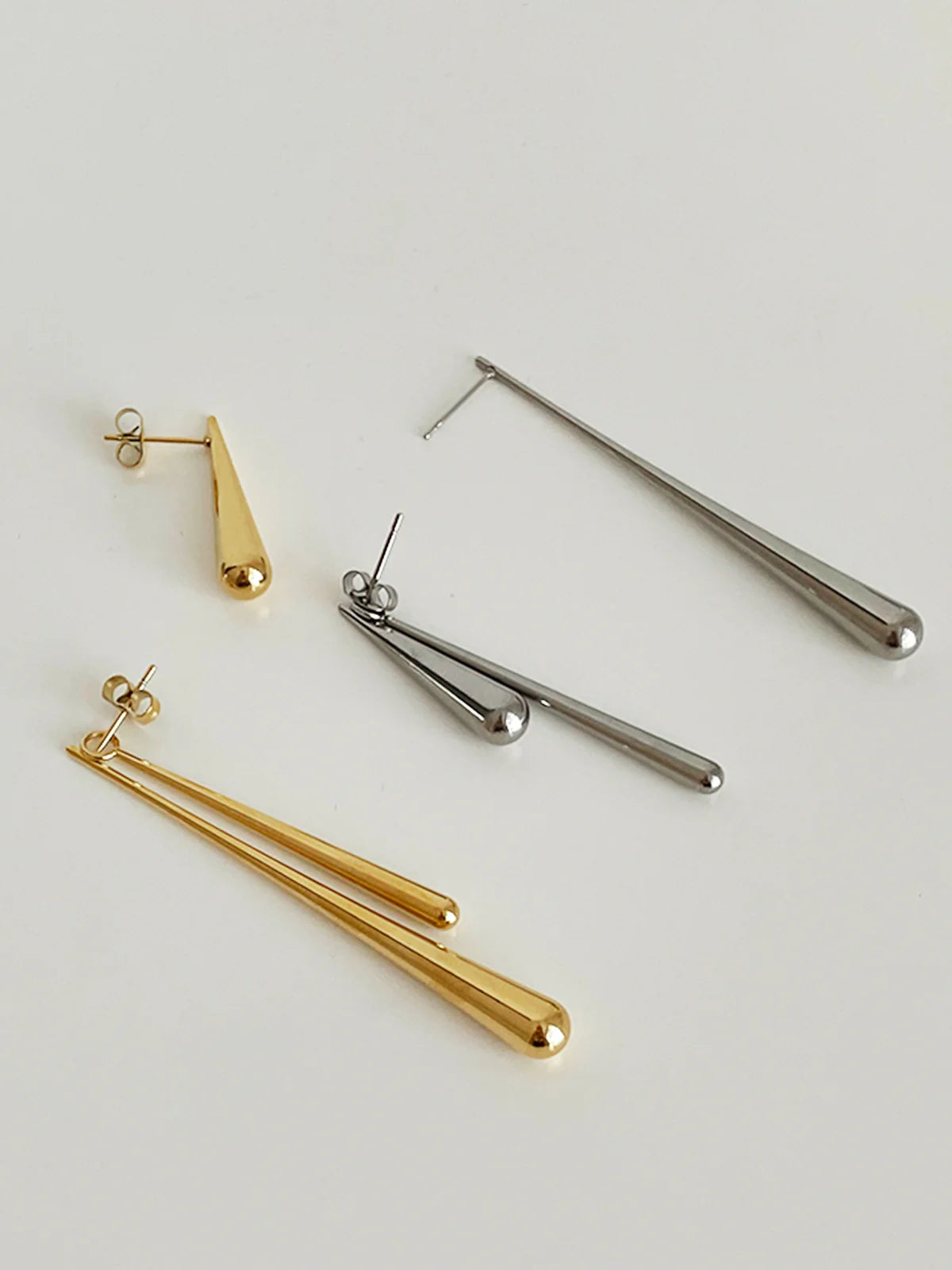 Ein-Paar-schlank-silber-gold-tropfenförmige-Ohrringe-an-einem-Ohr.